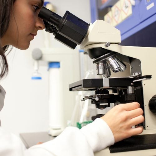 woman looking into a microscope