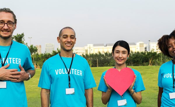 a diverse group of volunteers hold cutout hearts