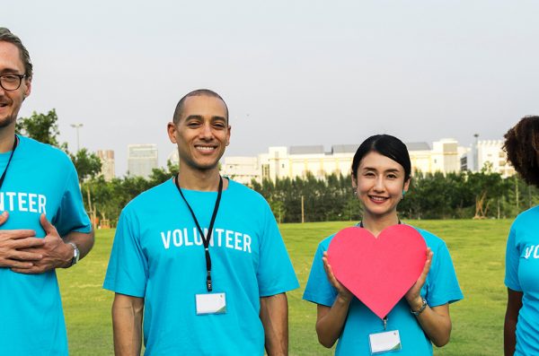 a group of volunteers stand together holding paper hearts