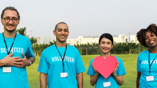 a group of volunteers stand together holding paper hearts