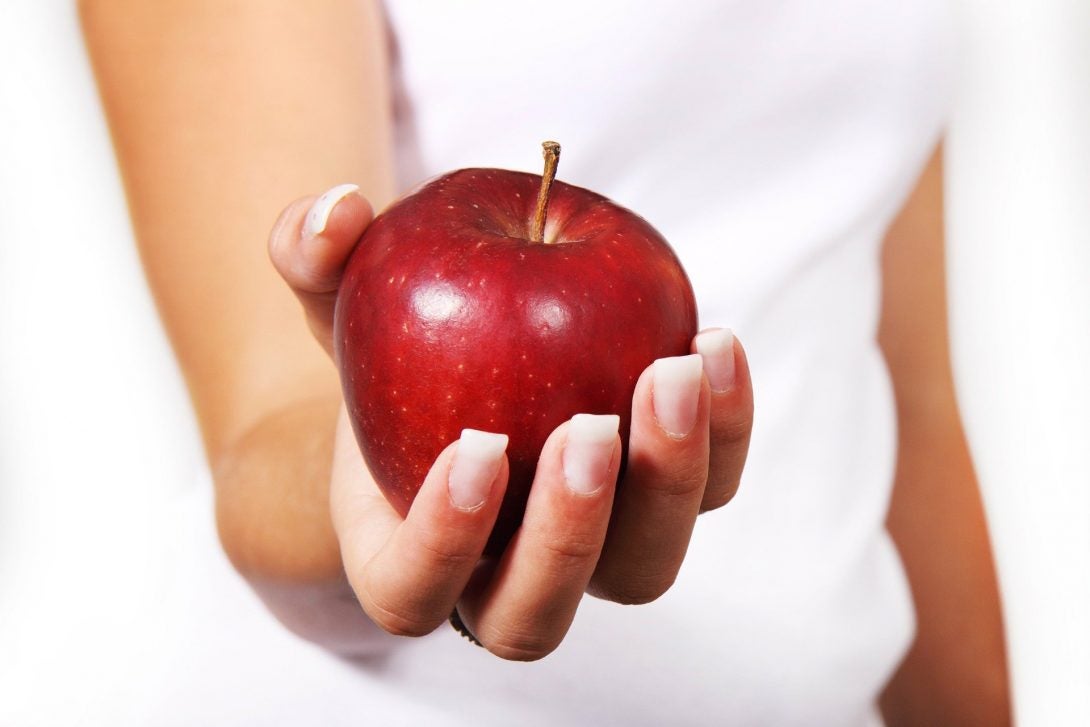 a woman's hand offers a red apple