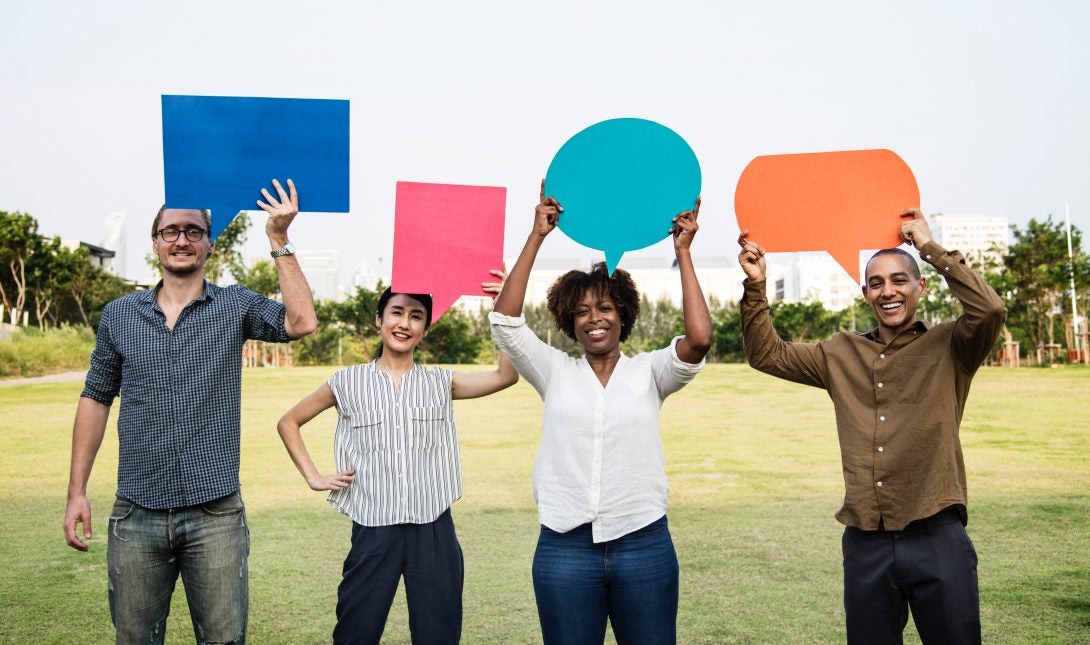 a diverse group of men and women hold up speech bubble cut outs