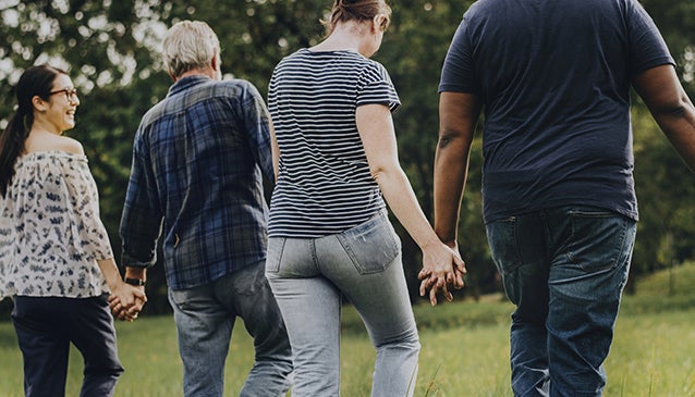 a diverse group of men and women walking hand in hand with their backs to the camera