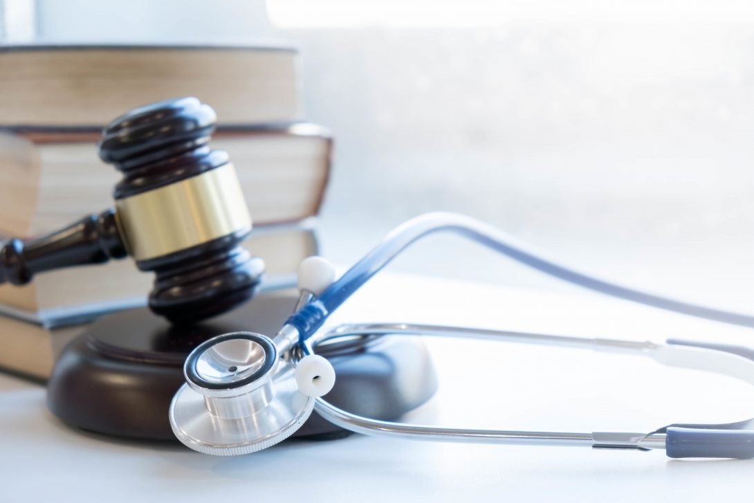 books and a judge's gavel behind a stethoscope