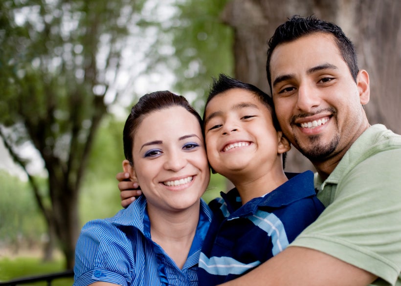 a man and woman hug their son while smiling at the camera