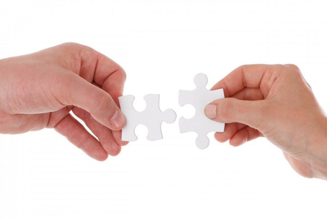 two hands connect puzzle pieces