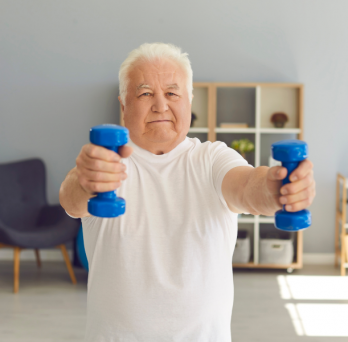 older adult male exercising with weights at home. photo courtesy of Canva. 
