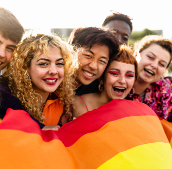 a group young LGBTQ people celebrate pride month with a rainbow flag 