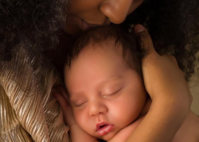 a mother kisses the top of her infant's head