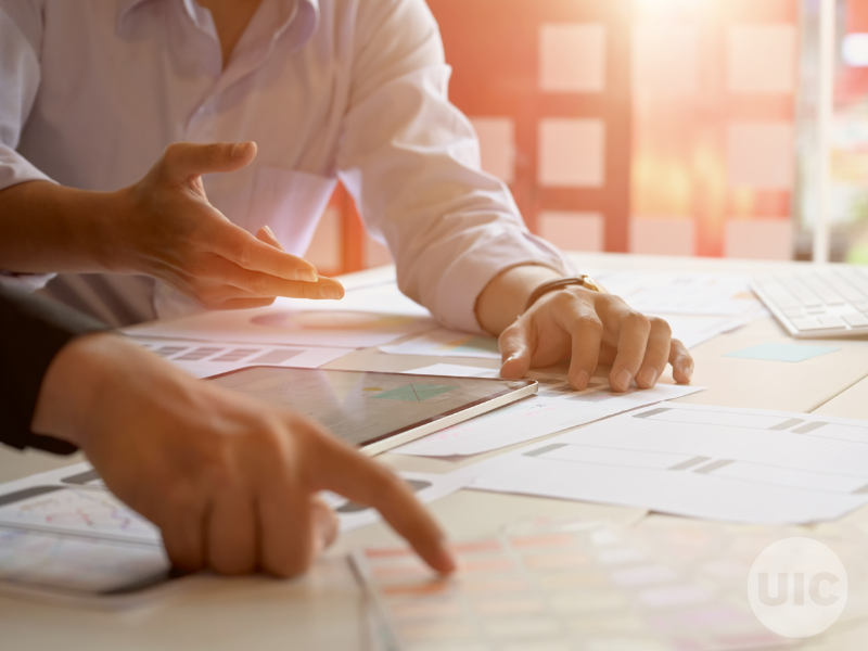 two people review paperwork on a desk. Bongkarn Thanyakij from Pexels for Canva