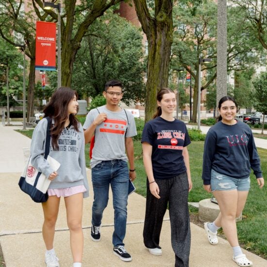 Four UIC Students smiling walking on UIC campus