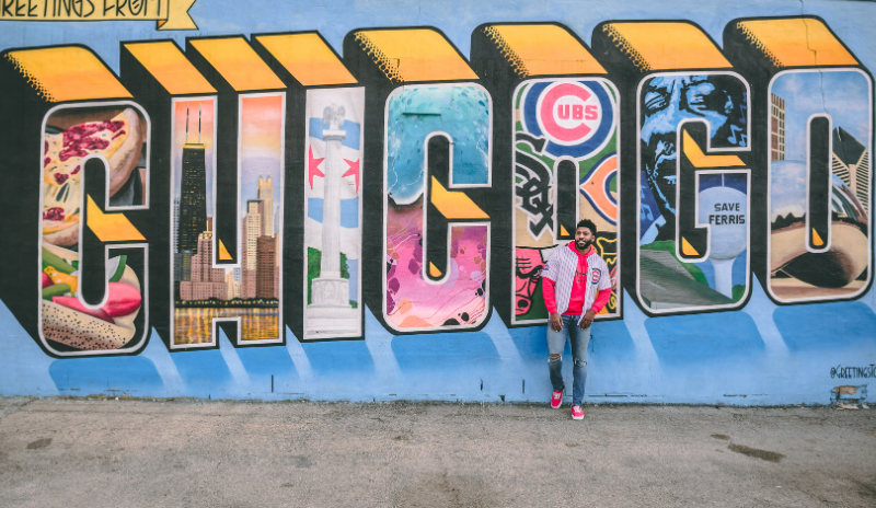 A man wearing a cubs jersey stands in front of a Chicago street mural. Image credit: Chait Goli for Pixels