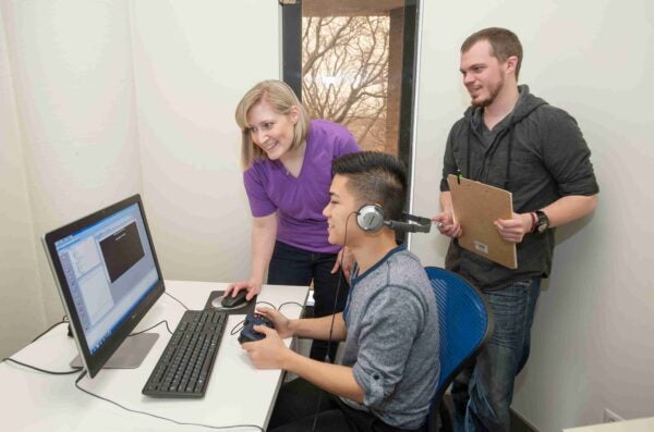 three researchers smiling working on a computer